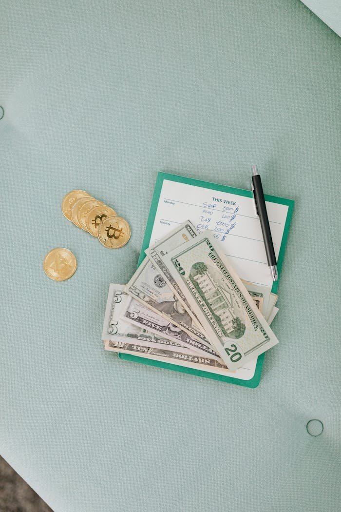 Close-up of US dollar bills, bitcoins, and a pen on calendar planner.